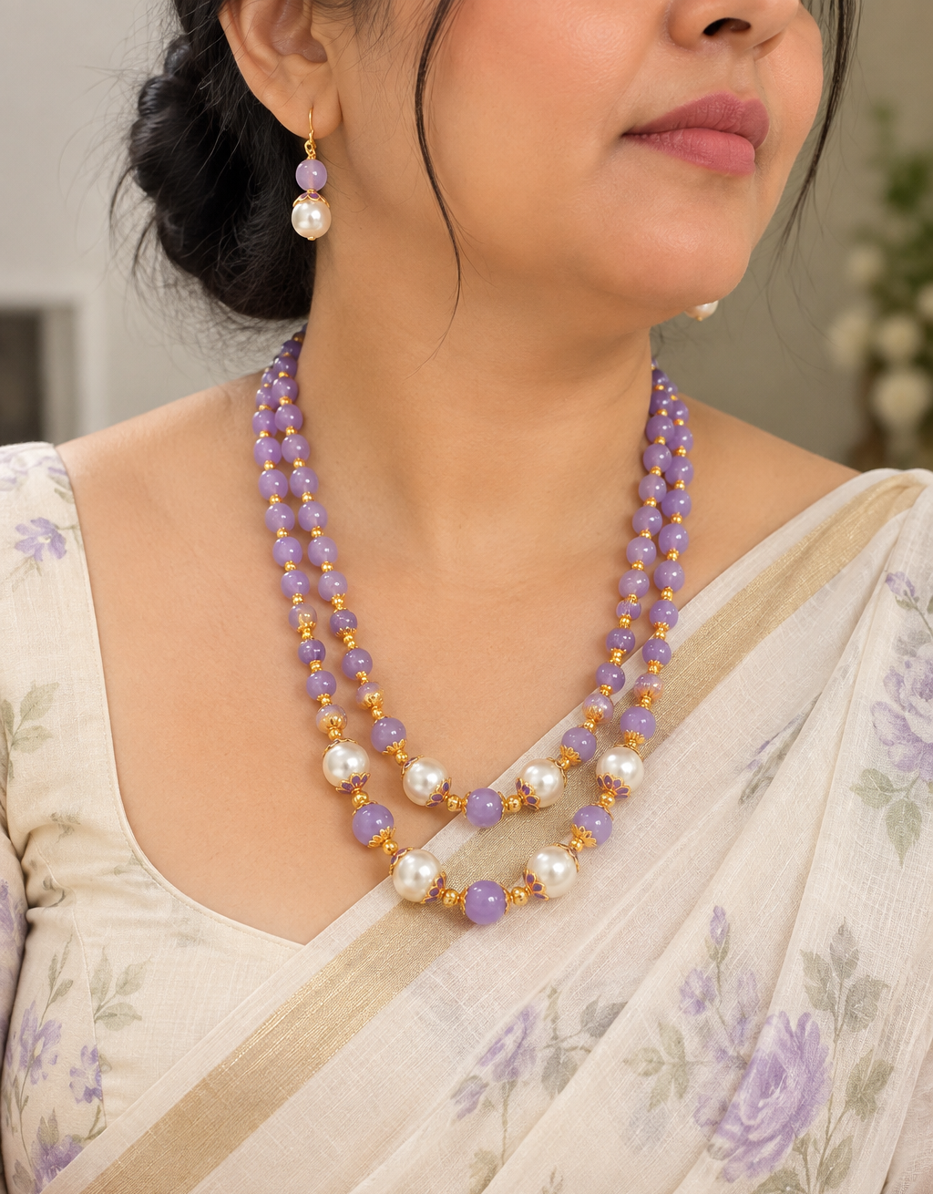 A close-up of a woman wearing a double-strand beaded necklace and matching drop earrings. The jewelry features lavender purple beads, white pearls, and small gold spacer beads.