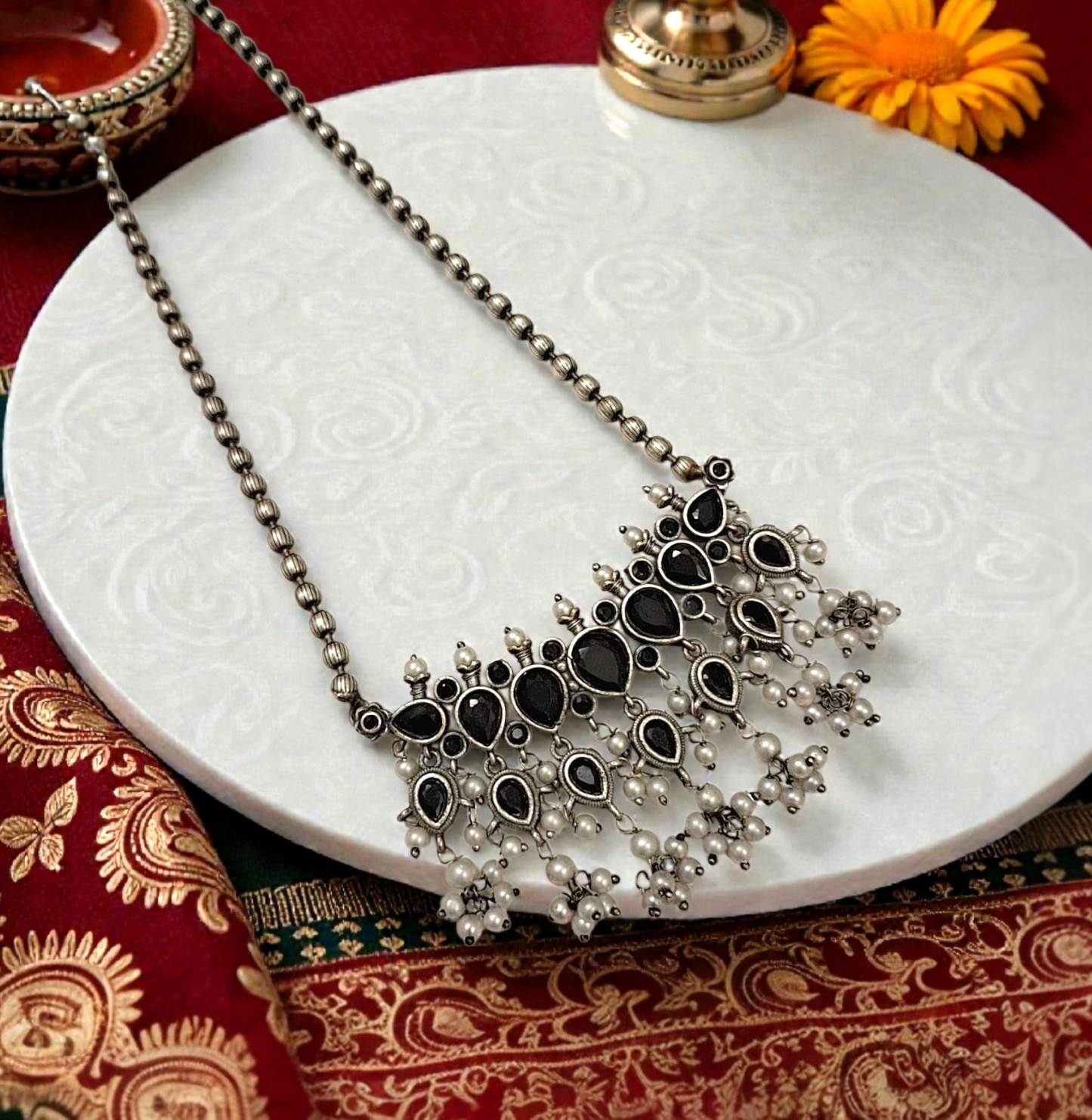 This oxidised black stone necklace set features antique silver finish detailing with pearl drops and matching earrings. Ideal ethnic statement jewellery for festive wear, weddings and traditional styling.