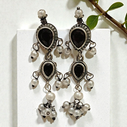 This oxidised black stone necklace set features antique silver finish detailing with pearl drops and matching earrings. Ideal ethnic statement jewellery for festive wear, weddings and traditional styling.