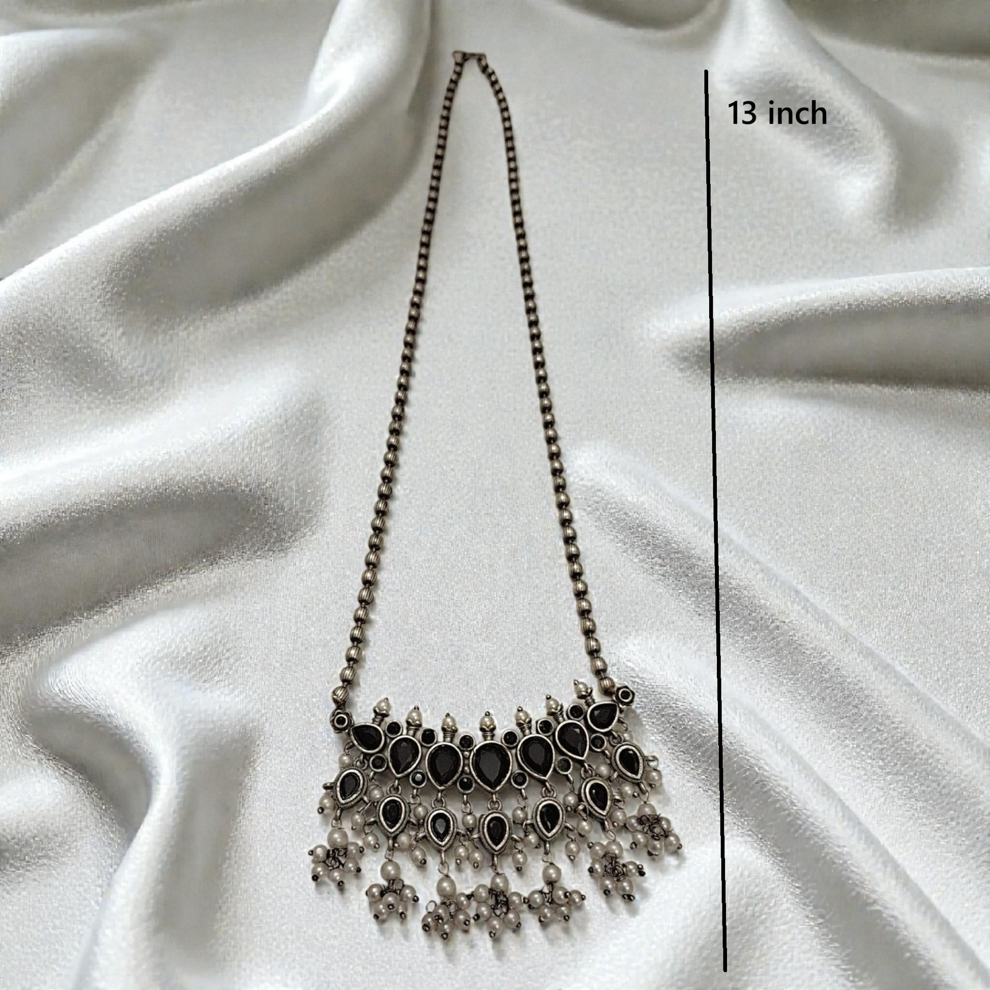 This oxidised black stone necklace set features antique silver finish detailing with pearl drops and matching earrings. Ideal ethnic statement jewellery for festive wear, weddings and traditional styling.