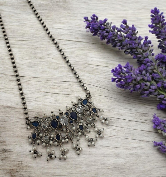 This oxidised blue and white stone necklace set features antique silver finish detailing with pearl drops and matching earrings. Ideal vintage ethnic statement jewellery for festive wear, weddings and traditional styling.